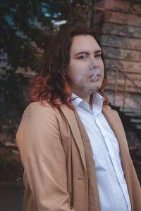 Portrait of woman smoking while standing outdoors