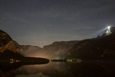 Scenic view of lake and mountains against sky at night