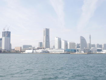 Sea by modern buildings against sky in city