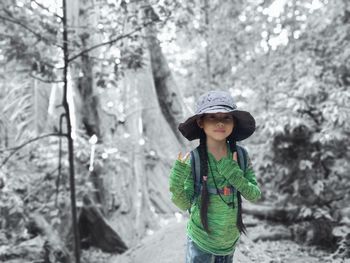 Portrait of happy girl standing by tree in forest