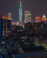 Illuminated buildings in city against sky at night