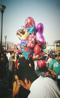 People with colorful balloons against sky