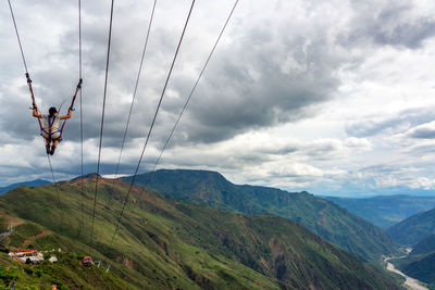 Woman swinging on giant swing against cloudy sky at chicamocha canyon