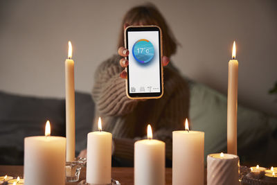 Woman lighting candles and using temperature app