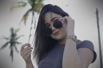 Portrait of young woman holding sunglasses