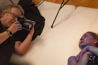 Portrait of man holding camera while sitting on floor