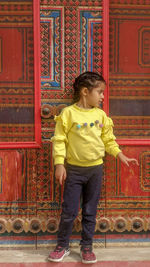 Full length of woman standing against red wall