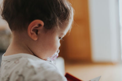 Side view of cute baby girl looking away at home