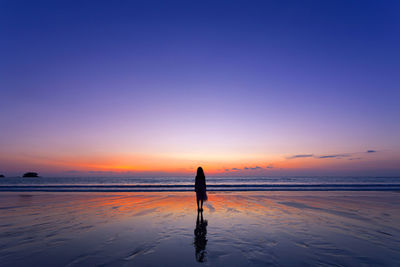 Girl standing at beach during sunset