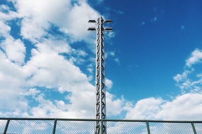 Low angle view of floodlight and chainlink fence against sky