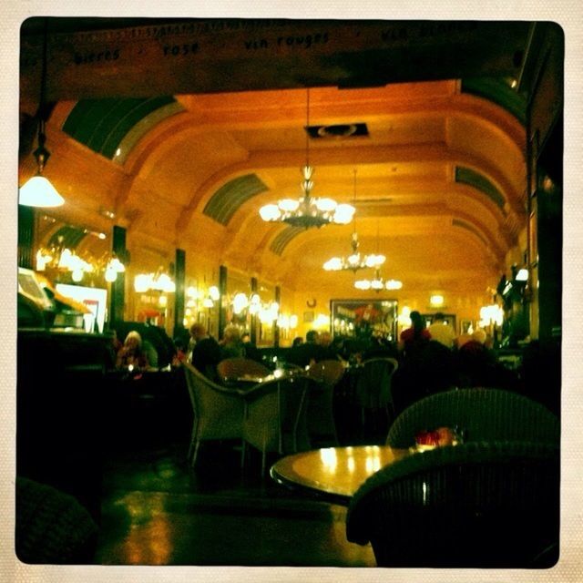 transfer print, indoors, auto post production filter, illuminated, lighting equipment, architecture, night, built structure, chair, table, incidental people, restaurant, potted plant, no people, decoration, ceiling, person, electric lamp, glass - material, light - natural phenomenon