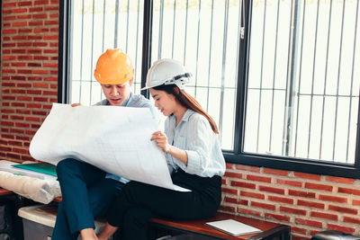 Man and woman wearing hat against window