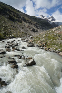 Scenic view of river flowing amidst mountains against sky