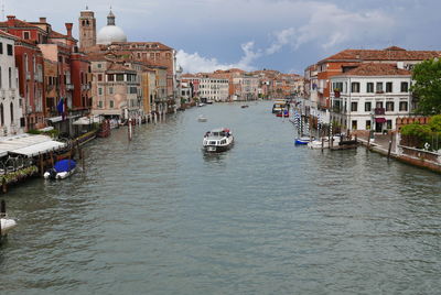 Sailboats moored on canal amidst buildings in city