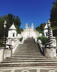 Low angle view of steps amidst buildings against clear blue sky