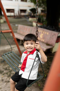 Portrait of cute boy sitting on swing