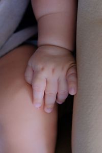 Midsection of baby lying on sofa at home