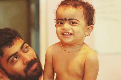 Portrait of smiling shirtless son with father at home