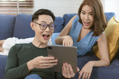 Young woman using mobile phone while sitting on sofa