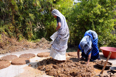 Rear view of people walking on road amidst trees