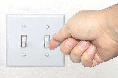 Close-up of person holding hands against white wall