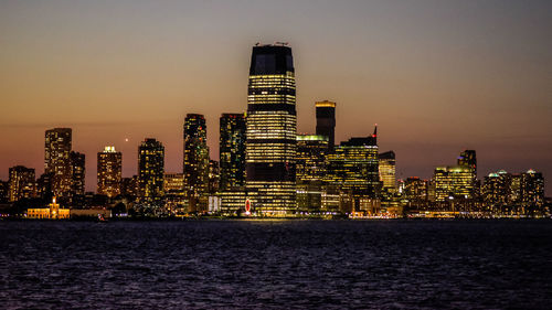 Illuminated buildings in city against sky during sunset