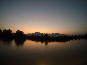 Scenic view of lake against clear sky during sunset