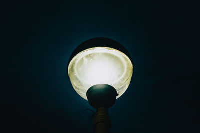 Low angle view of illuminated light bulb against black background