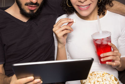 Midsection of woman and man using digital tablet at home
