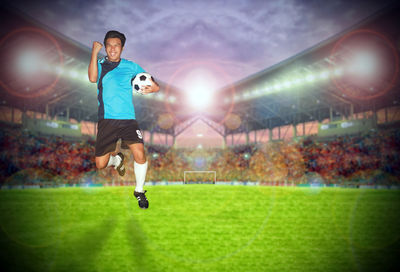 Happy player with soccer ball jumping on stadium