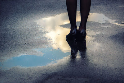 Low section of man standing on wet beach