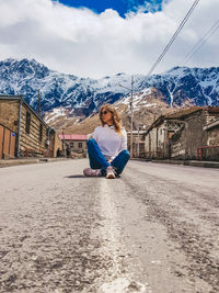 Sitting on snowcapped mountain against sky