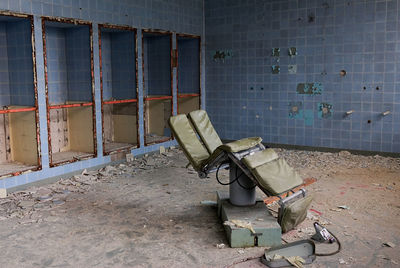 Old dentist chair against wall in abandoned building