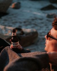 Young man sitting on bottle at beach