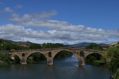 Arch bridge over river against sky