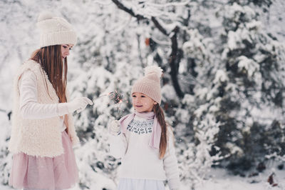 Playful sisters holding sparkler during winter