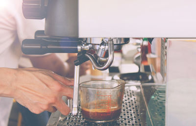 Close-up of hand pouring coffee in cafe