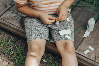 Close-up of child's leg injury. injured his knee. boy puts band-aid on wound after falling in street