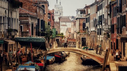 Boats in canal amidst buildings in city