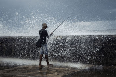 Man fishing while standing at sea shore