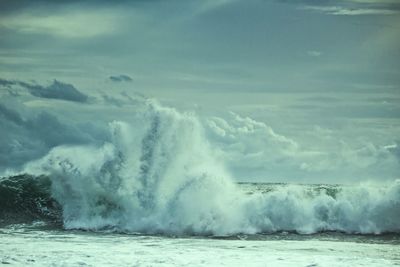 Waves splashing on sea against sky