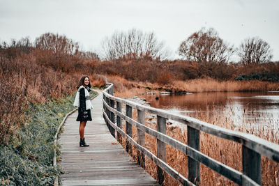 Woman standing on footbridge against clear sky