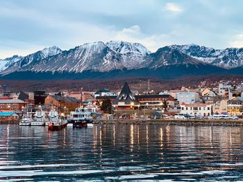 Scenic view of townscape by mountains against sky