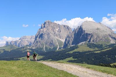 Rear view of people hiking by dolomites mountains