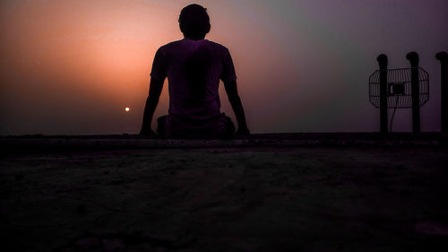 Rear view of silhouette man standing against sky during sunset