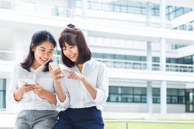 Happy woman using mobile phone in laptop