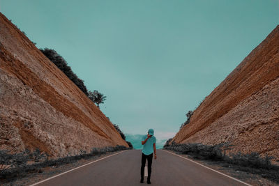 Rear view of man standing on road against sky