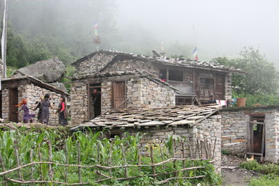 Houses and trees in village against sky