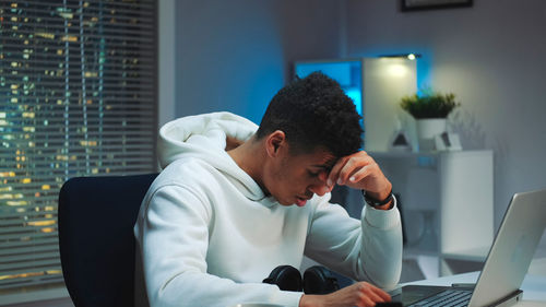 Side view of woman using laptop at home