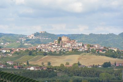 Scenic view of village in piedmont against cloudy sky